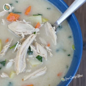 Creamy chicken spinach soup in a bowl, garnished with fresh herbs.